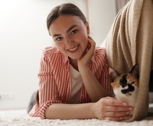 Photo of Woman with her cute calico kitten on floor at home