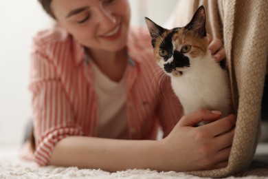 Photo of Woman with her cute calico kitten on floor at home, selective focus