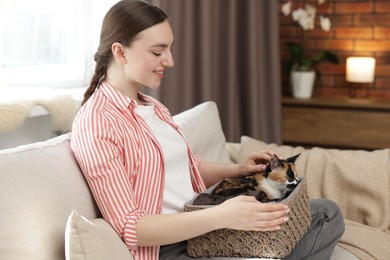 Photo of Woman with her cute calico kitten on sofa at home