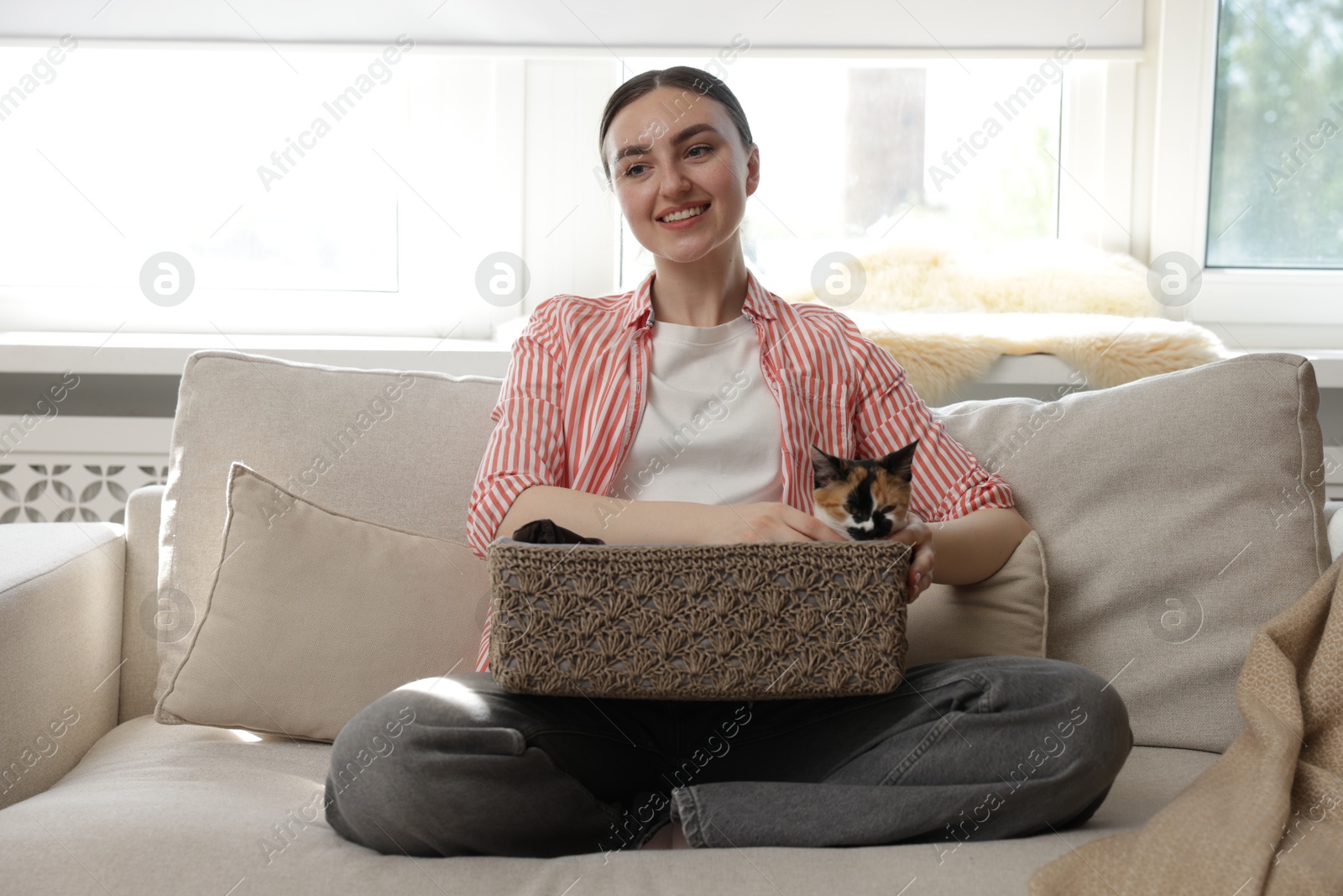 Woman with her cute calico kitten on sofa at home Photo of Woman with her cute calico kitten on sofa at home