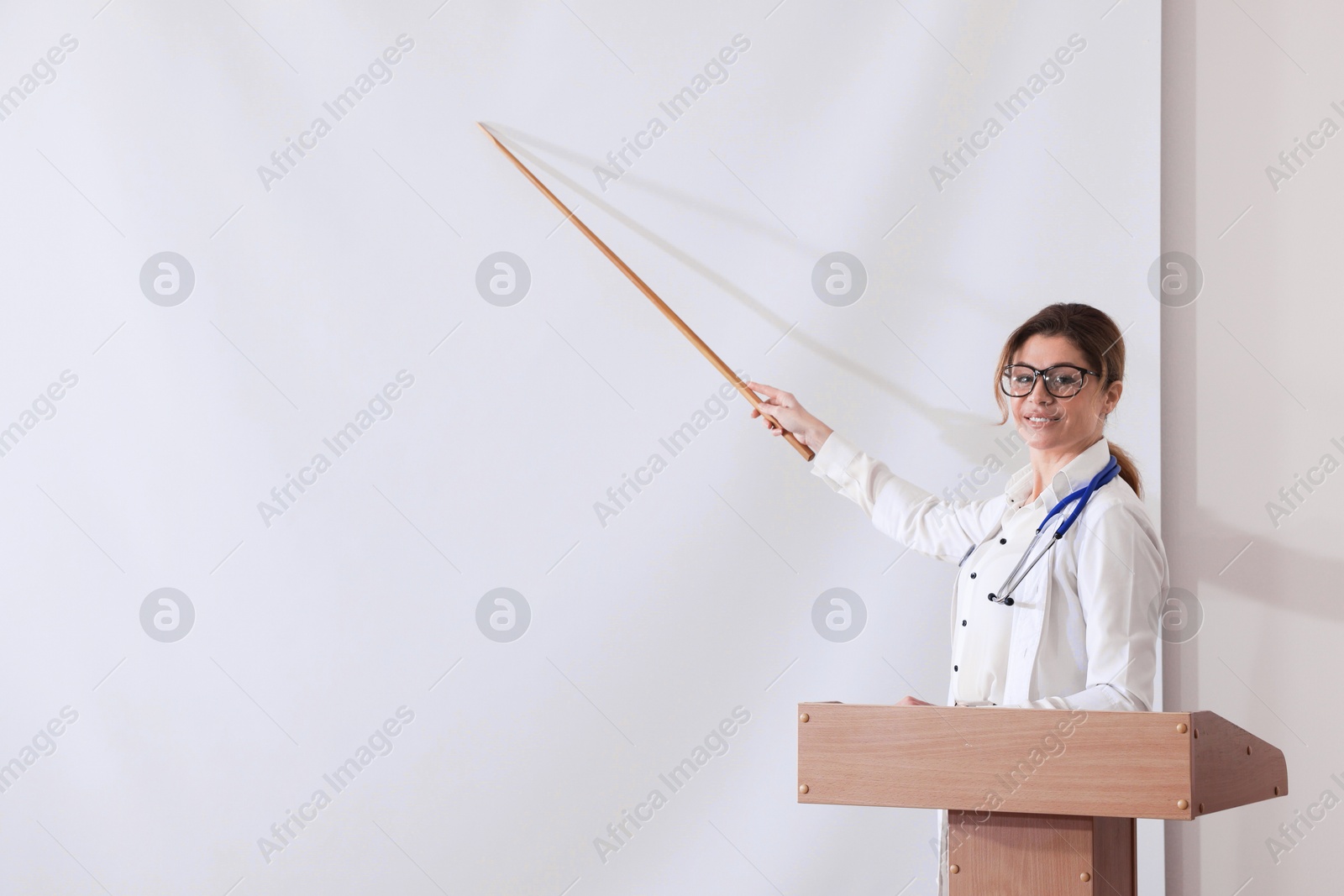 Doctor giving lecture near projection screen in conference room, space for text Photo of Doctor giving lecture near projection screen in conference room, space for text