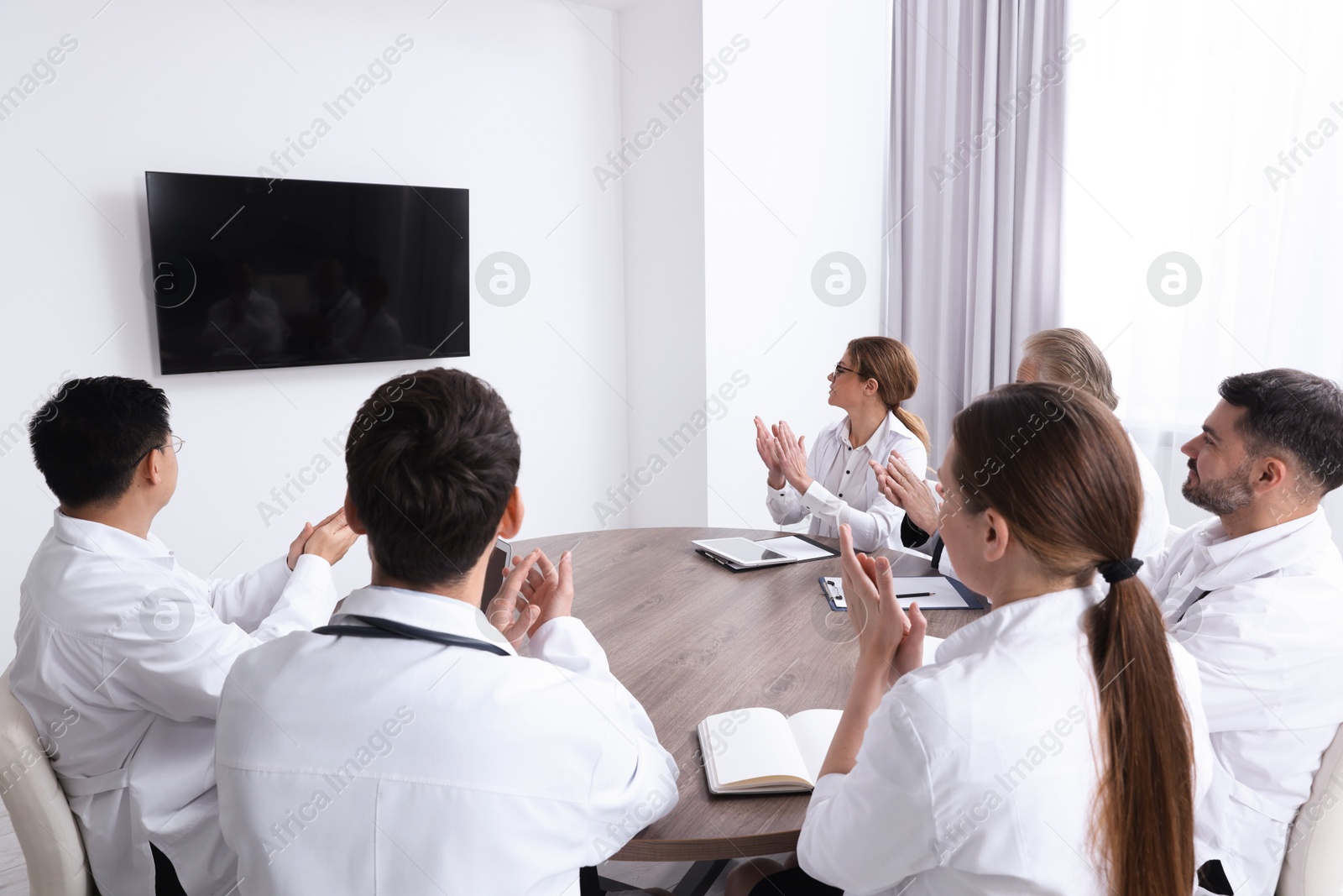 Team of doctors watching presentation on tv screen in room. Medical conference Photo of Team of doctors watching presentation on tv screen in room. Medical conference