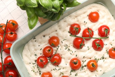 Photo of Raw focaccia with tomatoes and spices on table, flat lay
