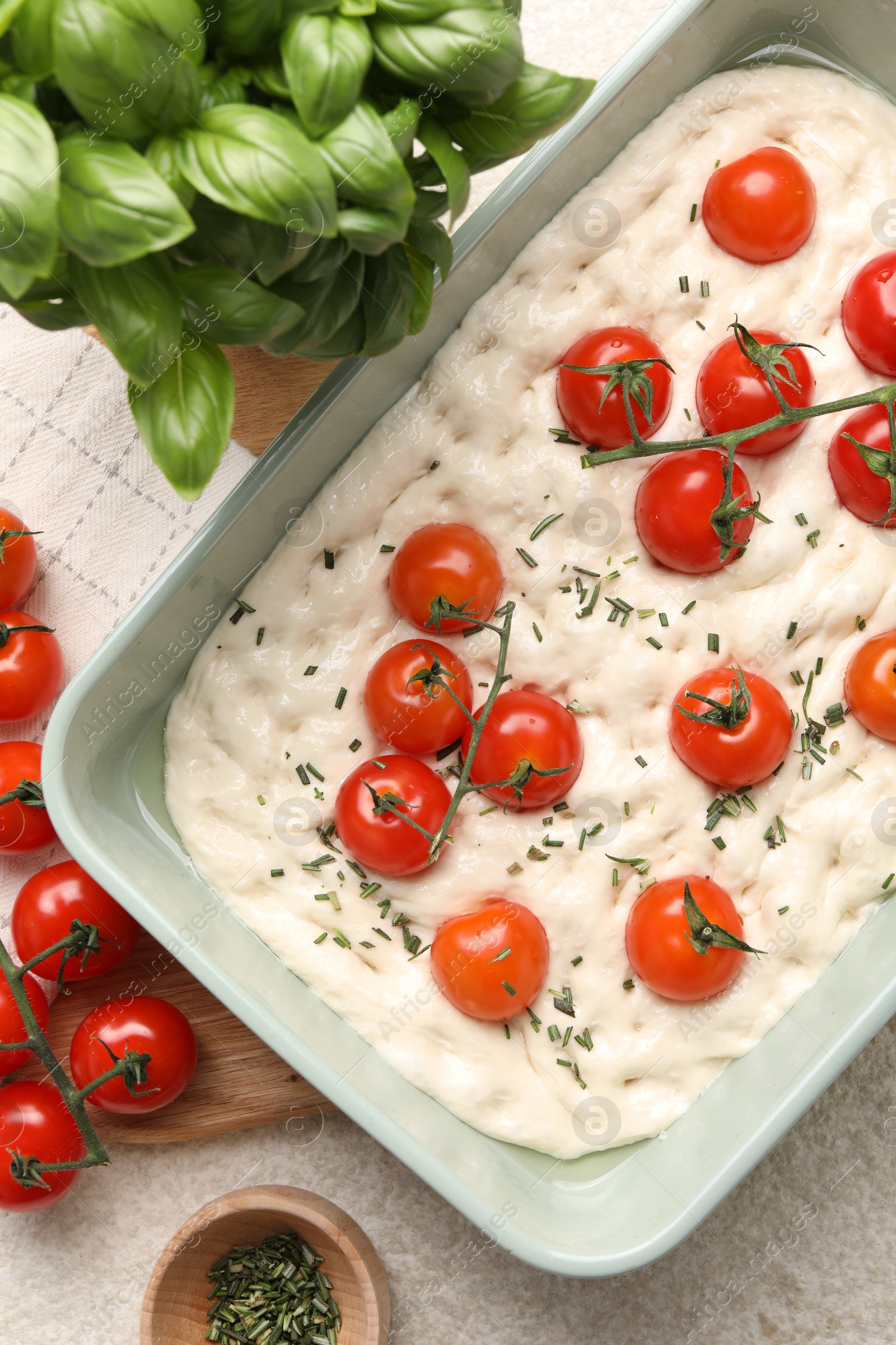 Raw focaccia with tomatoes and spices on light textured table, flat lay Photo of Raw focaccia with tomatoes and spices on light textured table, flat lay