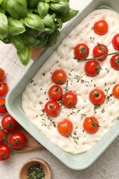 Photo of Raw focaccia with tomatoes and spices on light textured table, flat lay
