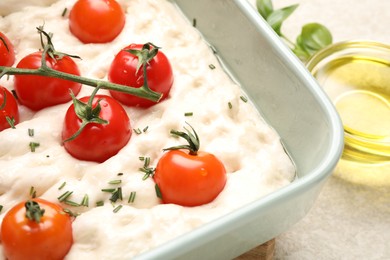 Photo of Raw focaccia with tomatoes and spices on light table, closeup
