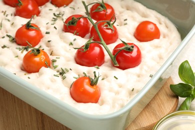 Photo of Raw focaccia with tomatoes and spices on table, closeup