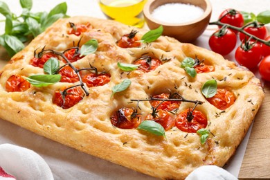 Photo of Delicious focaccia with tomatoes and spices on table, closeup