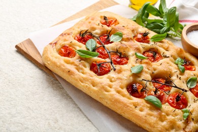 Photo of Delicious focaccia with tomatoes and spices on beige textured table, closeup