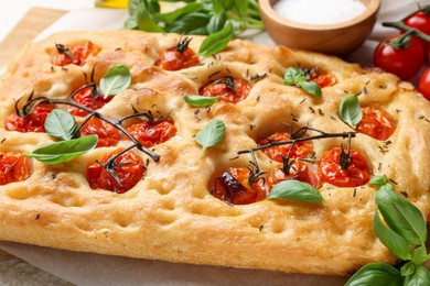 Photo of Delicious focaccia with tomatoes and spices on table, closeup