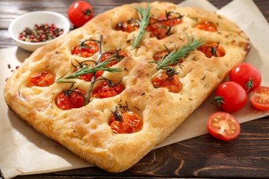 Photo of Delicious focaccia with tomatoes and spices on wooden table, closeup