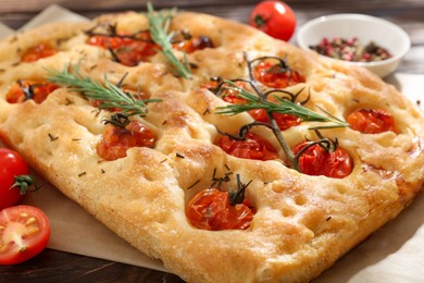 Photo of Delicious focaccia with tomatoes and spices on table, closeup