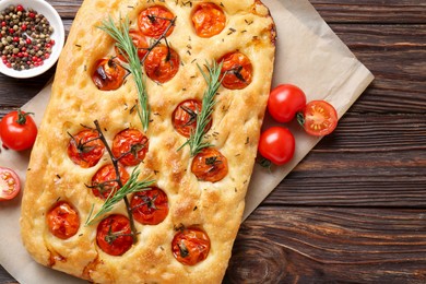 Photo of Delicious focaccia with tomatoes and spices on wooden table, flat lay