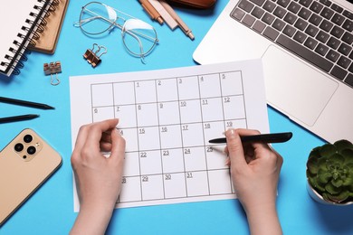 Photo of Woman with planner, stationery, laptop and smartphone on light blue background, top view