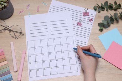 Photo of Woman with planner and stationery at wooden table, top view