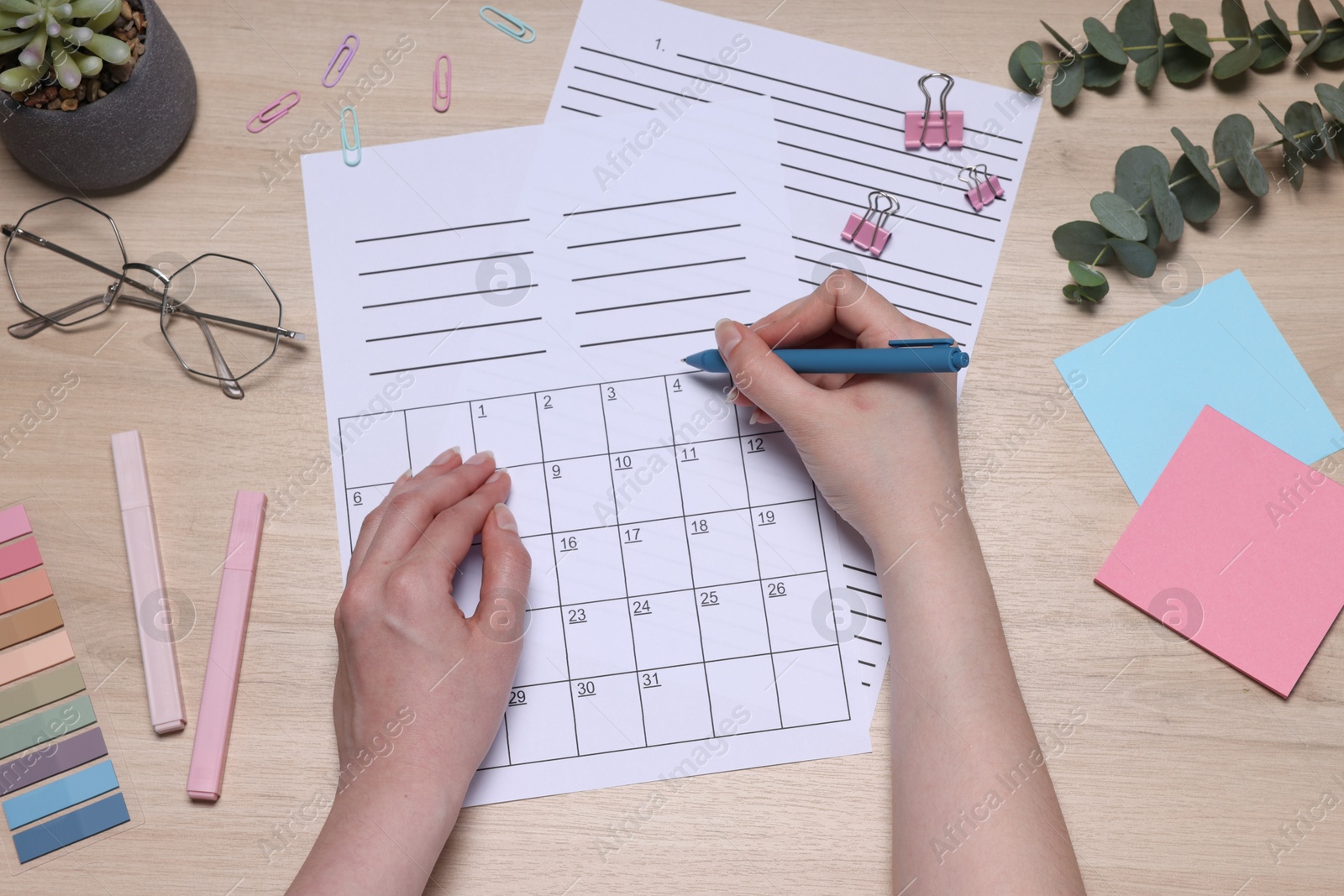 Woman with planner and stationery at wooden table, top view Photo of Woman with planner and stationery at wooden table, top view