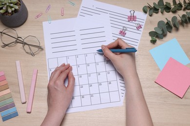 Photo of Woman with planner and stationery at wooden table, top view