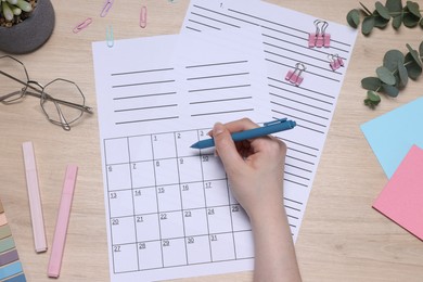 Photo of Woman with planner and stationery at wooden table, top view