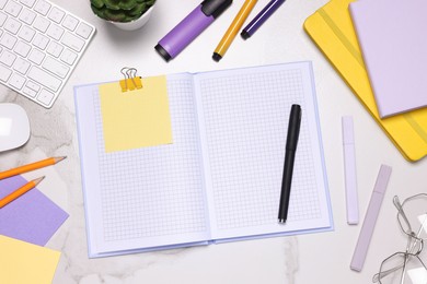 Photo of Open planner and stationery on light marble table, flat lay