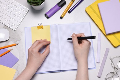 Photo of Woman with planner and stationery at light marble table, top view