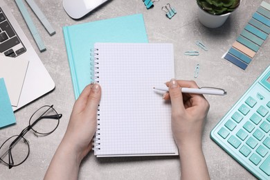 Photo of Woman with planner and stationery at grey textured table, top view