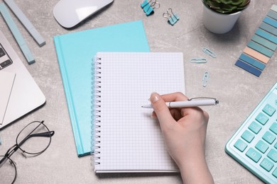 Photo of Woman with planner and stationery at grey textured table, top view