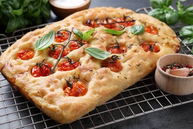 Photo of Delicious focaccia with tomatoes and spices on table, closeup