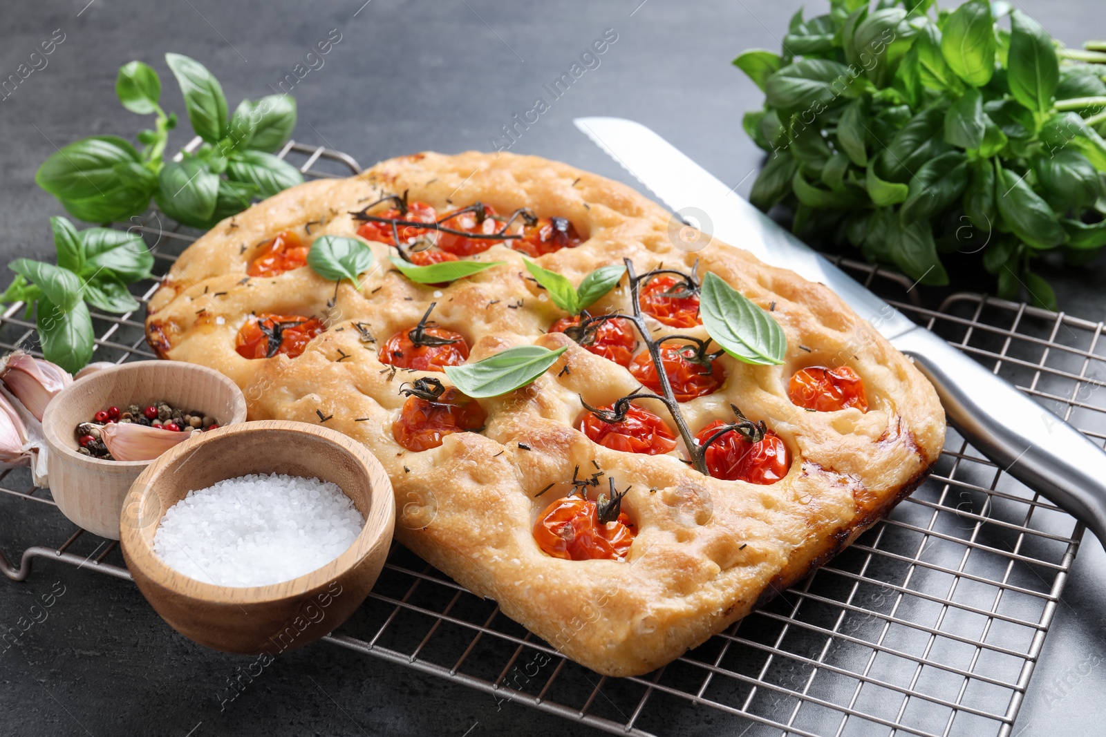 Delicious focaccia with tomatoes, spices and knife on table, closeup Photo of Delicious focaccia with tomatoes, spices and knife on table, closeup