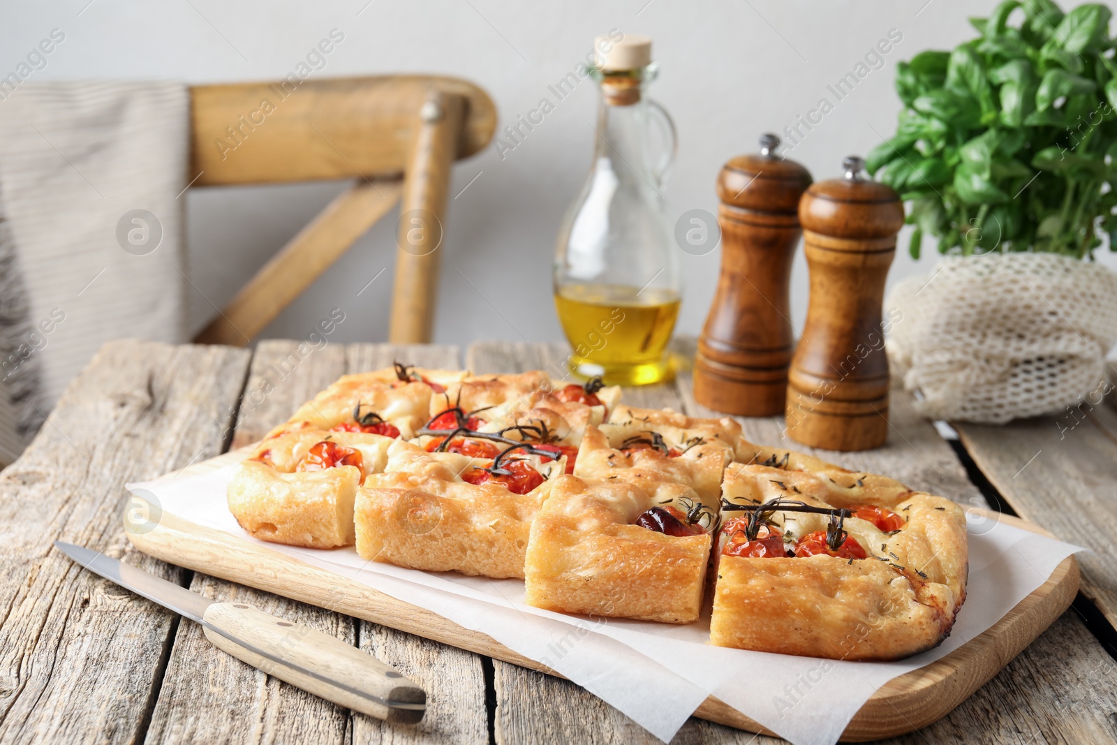 Cut delicious focaccia with tomatoes, spices and oil on wooden table indoors Photo of Cut delicious focaccia with tomatoes, spices and oil on wooden table indoors