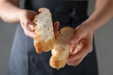 Photo of Woman holding pieces of delicious focaccia with tomatoes on gray background, closeup