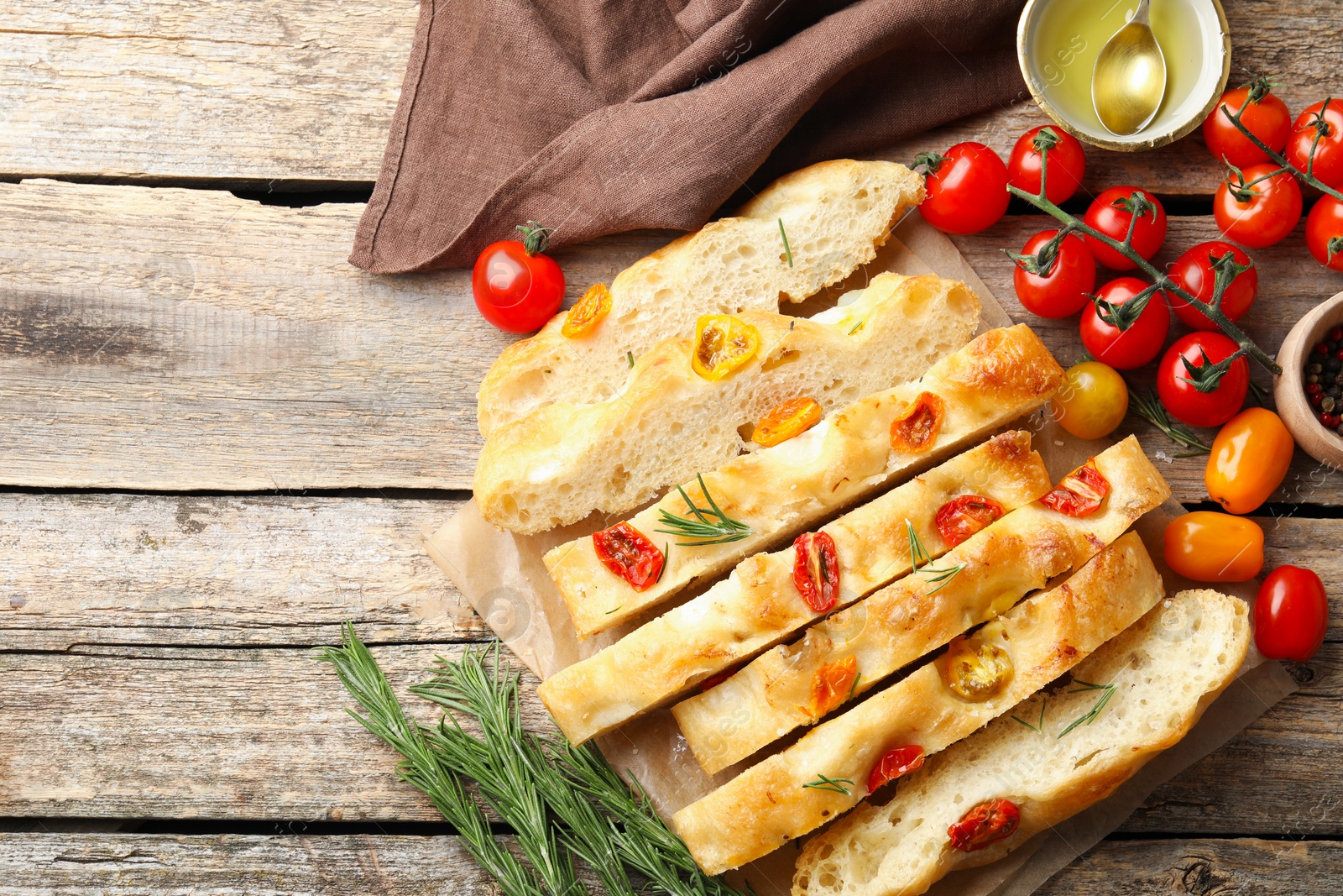Cut delicious focaccia with tomatoes, spices and oil on wooden table, flat lay. Space for text Photo of Cut delicious focaccia with tomatoes, spices and oil on wooden table, flat lay. Space for text
