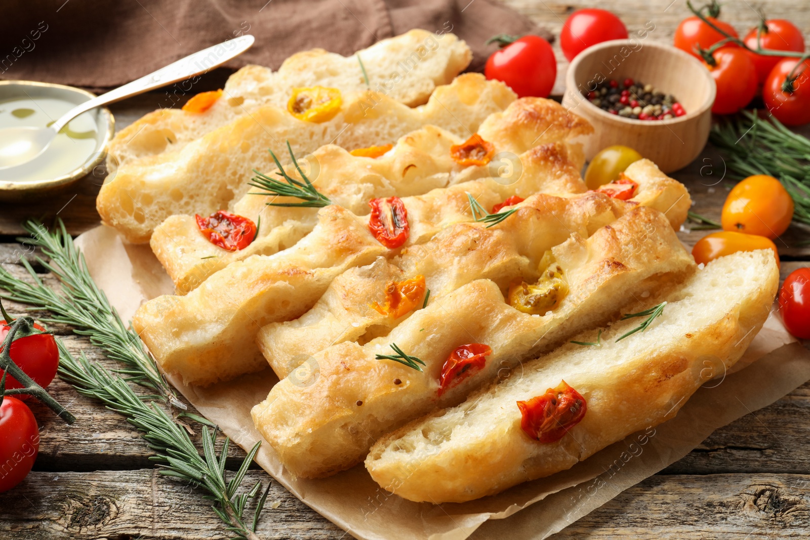 Cut delicious focaccia with tomatoes, spices and oil on wooden table, closeup Photo of Cut delicious focaccia with tomatoes, spices and oil on wooden table, closeup