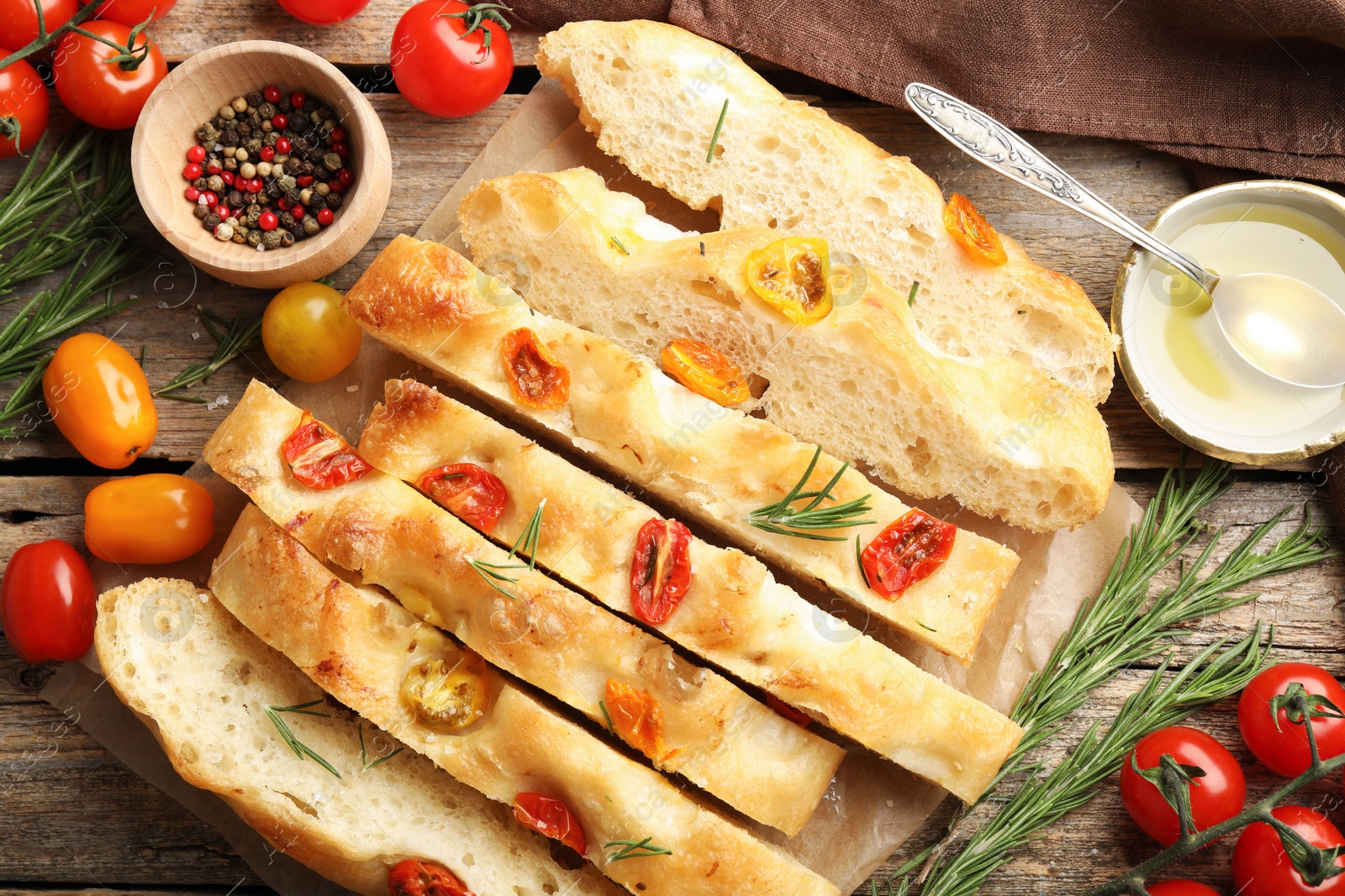 Cut delicious focaccia with tomatoes, spices and oil on wooden table, flat lay Photo of Cut delicious focaccia with tomatoes, spices and oil on wooden table, flat lay