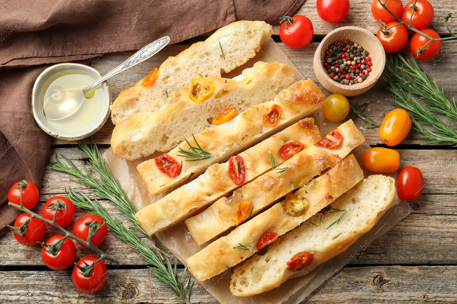 Cut delicious focaccia with tomatoes, spices and oil on wooden table, flat lay Photo of Cut delicious focaccia with tomatoes, spices and oil on wooden table, flat lay