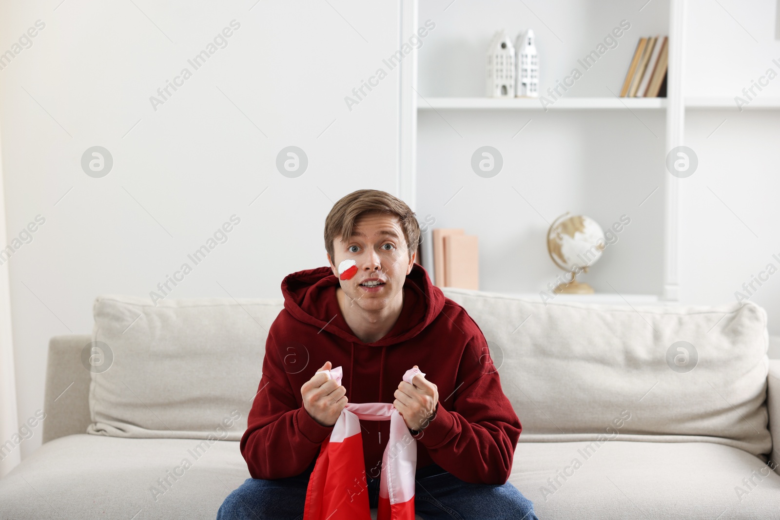 Emotional sports fan with flag of Poland watching game indoors Photo of Emotional sports fan with flag of Poland watching game indoors