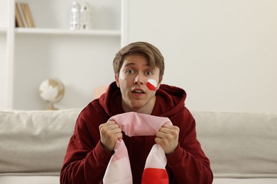 Photo of Emotional sports fan with flag of Poland watching game indoors