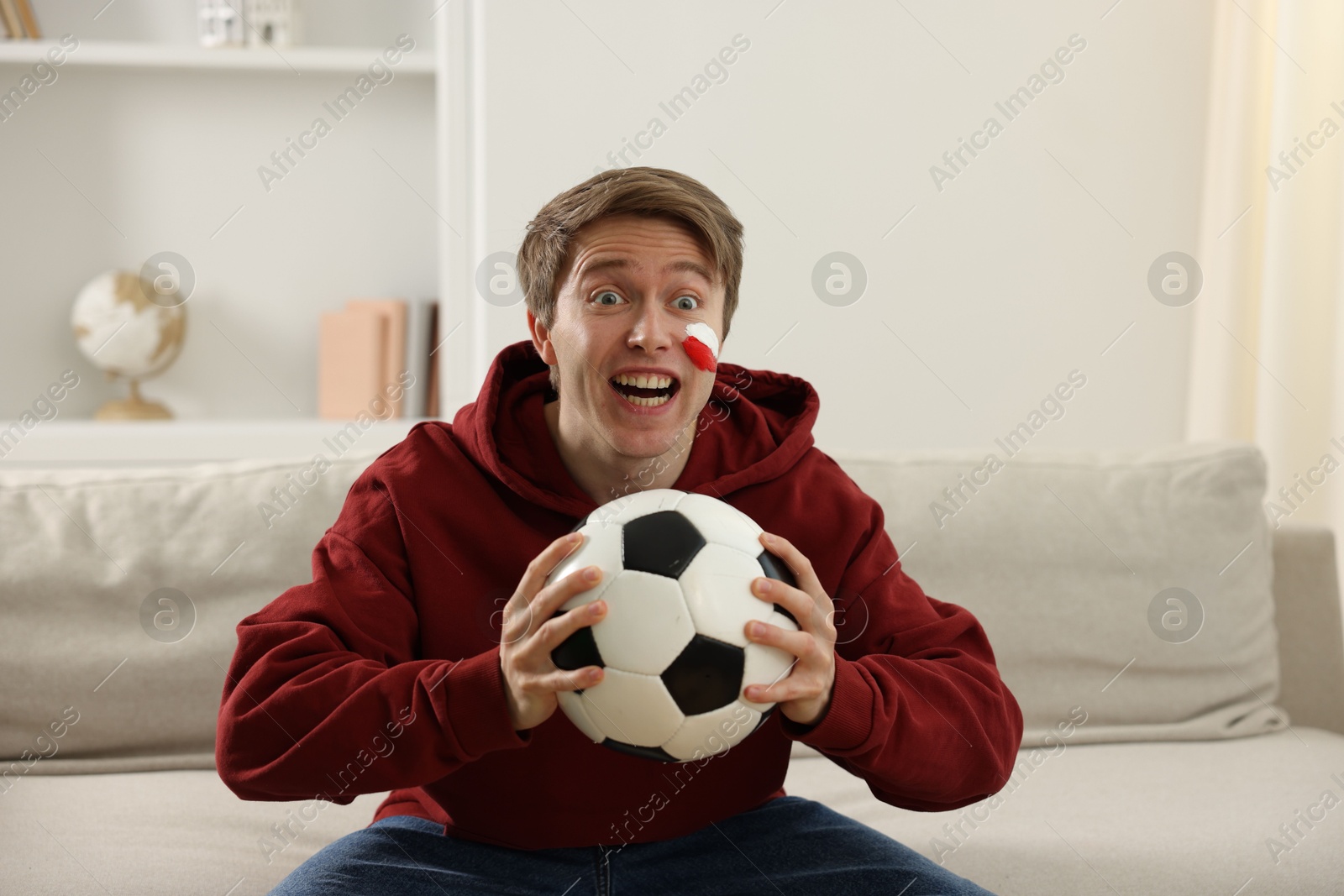 Emotional sports fan with soccer ball watching game indoors Photo of Emotional sports fan with soccer ball watching game indoors
