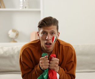 Photo of Sports fan with flag of Italy watching game on sofa indoors