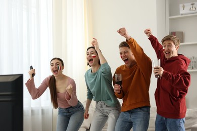 Photo of Emotional sports fans watching game together indoors