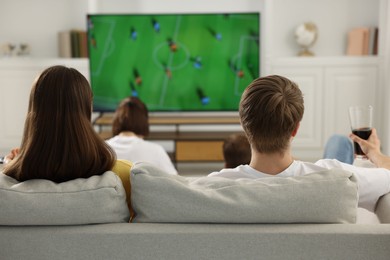 Photo of Group of football fans watching game together indoors, back view