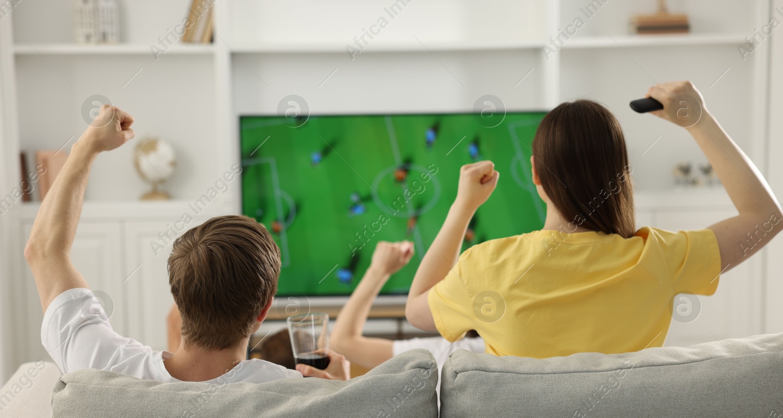 Group of football fans watching game together indoors, back view Photo of Group of football fans watching game together indoors, back view