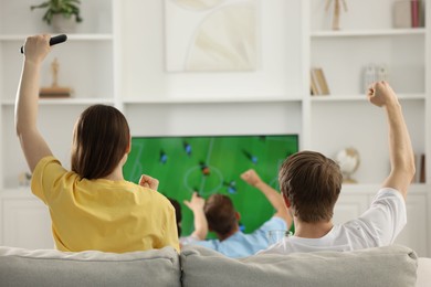 Photo of Group of football fans watching game together indoors, back view