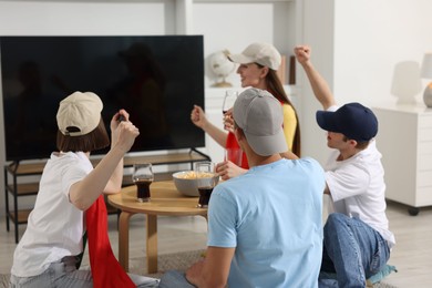 Photo of Emotional sports fans watching game together indoors, selective focus