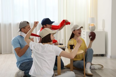 Photo of Emotional sports fans watching game together indoors