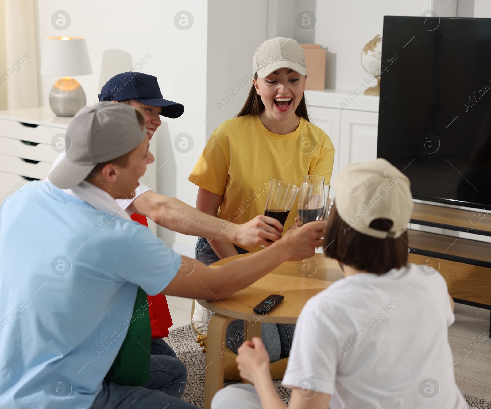 Emotional sports fans with drinks celebrating victory indoors Photo of Emotional sports fans with drinks celebrating victory indoors