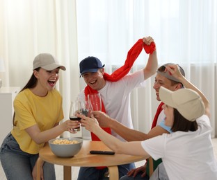 Photo of Emotional sports fans with drinks celebrating victory indoors