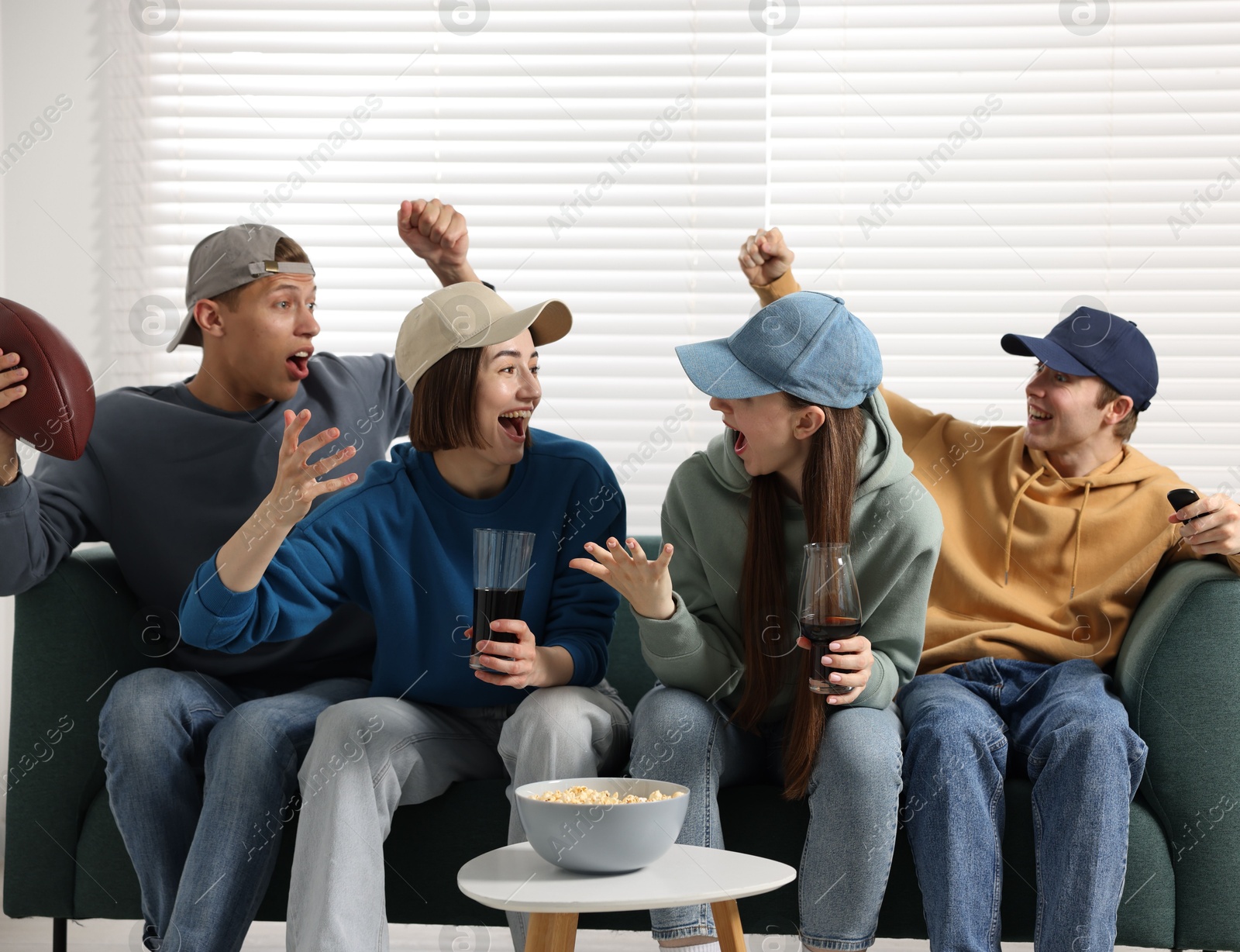 Emotional sports fans watching game together on sofa indoors Photo of Emotional sports fans watching game together on sofa indoors