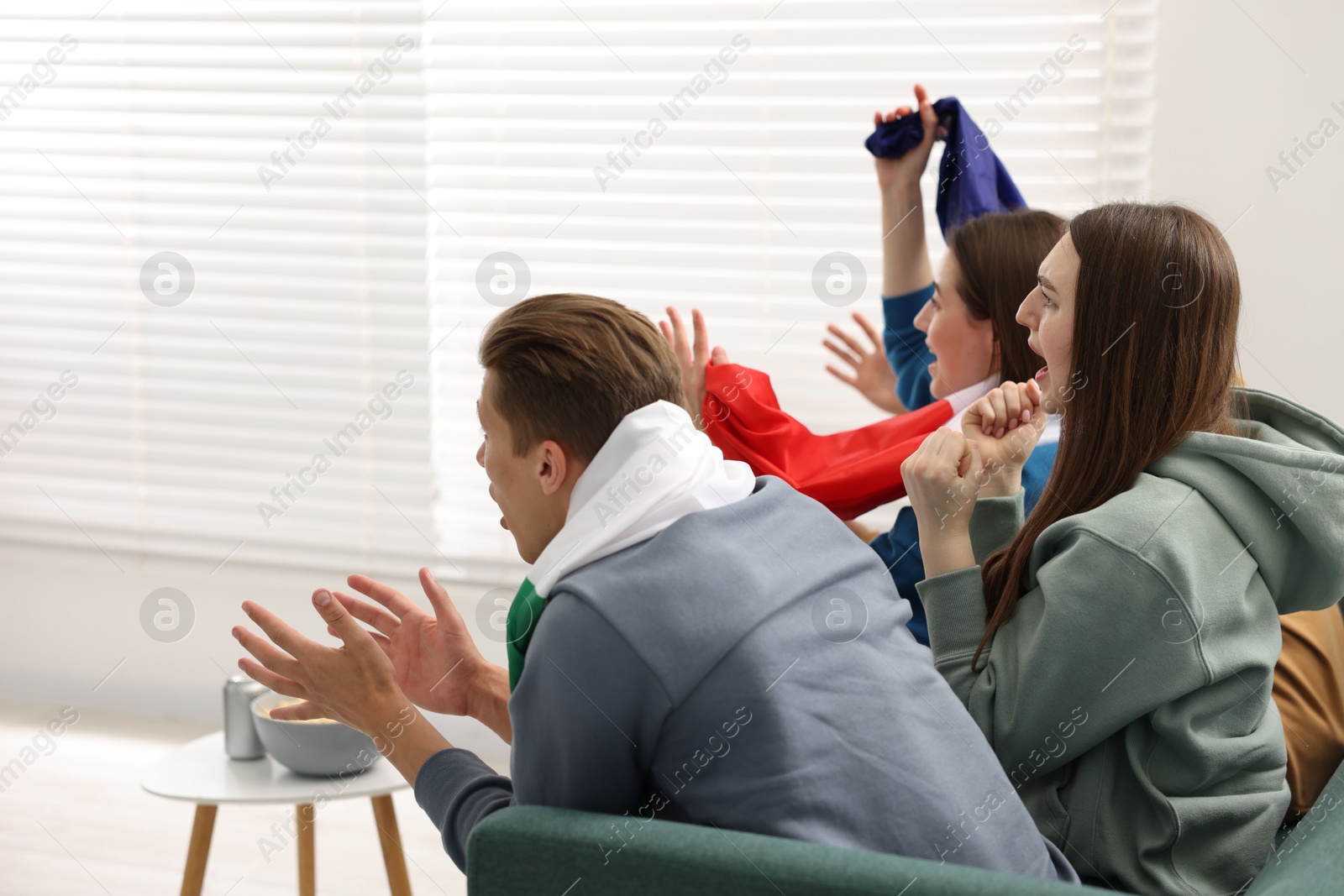 Emotional sports fans watching game together on sofa indoors Photo of Emotional sports fans watching game together on sofa indoors