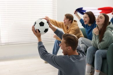 Photo of Emotional football fans watching game together indoors, selective focus. Space for text