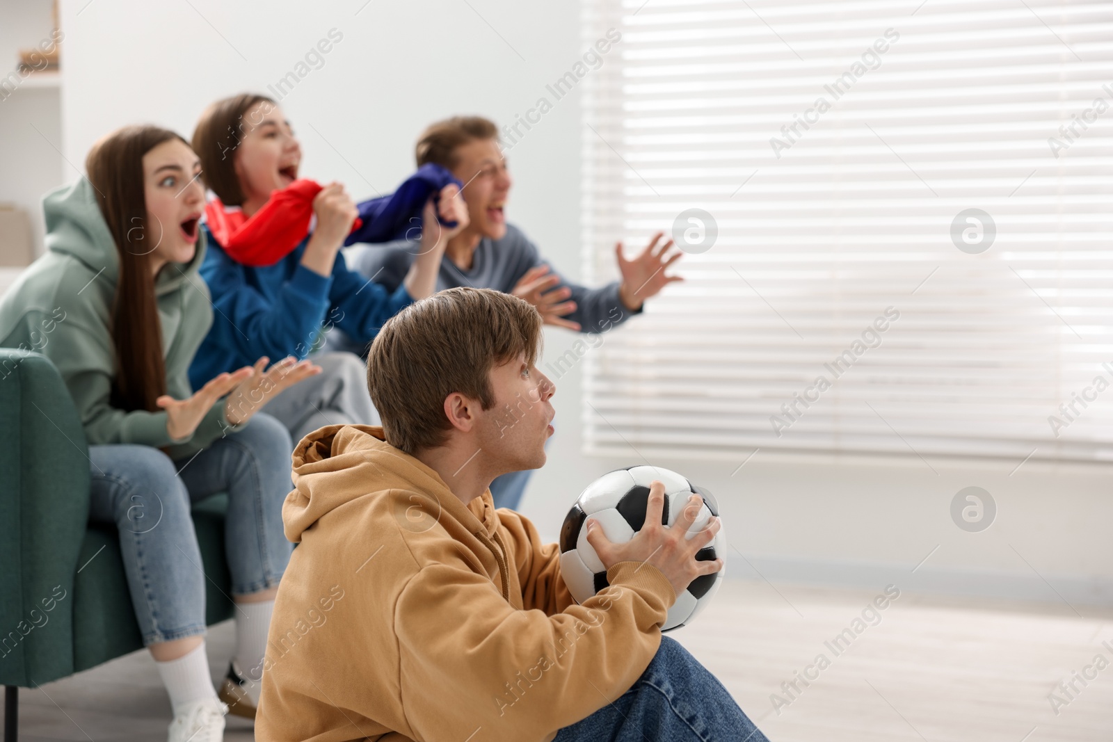 Emotional football fans watching game together indoors, selective focus. Space for text Photo of Emotional football fans watching game together indoors, selective focus. Space for text